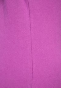 Tela morada con textura suave, con un detalle sencillo de costura. El material parece elástico y ajustado.