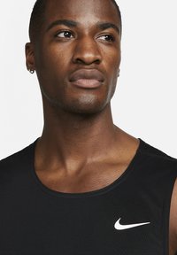 Mustmust šortseelik ümara kaelusega, sujuva kangaga ja sirgete õmblustega. Vasakul rinnal on valge Nike logo.