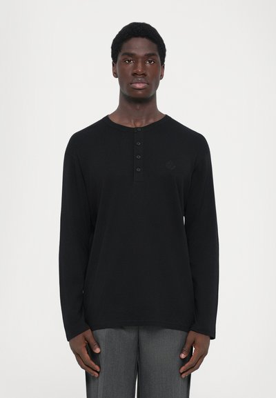 T-shirt henley noir à manches longues avec un col arrondi, un plastron à quatre boutons et un logo discret sur la poitrine. Tissu lisse et coupe décontractée.