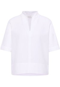 Blusa bianca a maniche corte con colletto alto, scollatura a V e vestibilità ampia. Realizzata in tessuto leggero, con una texture liscia.