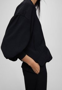 Zwarte sweatshirt met een ronde hals, oversized mouwen en geribde manchetten, met een soepele textuur en een relaxte pasvorm.