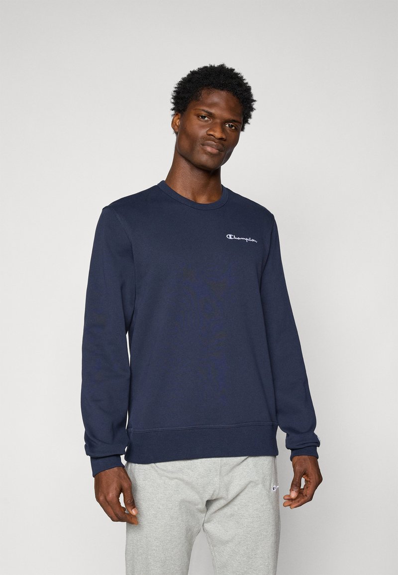 Mørkeblå sweatshirt med lange ærmer, der har en rund halsudskæring og hvidt broderet logo på brystet. Blødt, struktureret stof.