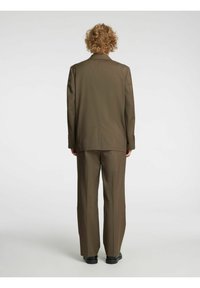 Bruin pak met een gestructureerde afwerking, bestaande uit een getailleerde blazer en bijpassende wijde broekspijpen. Fijn patroon en standaard reversdetails.