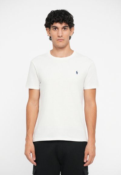 T-shirt de algodão branco com mangas curtas, decote redondo e pequeno logótipo azul bordado no lado esquerdo do peito. Textura suave, ajuste relaxado.