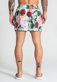 Shorts de bain pour homme en tissu blanc orné d'un motif floral et d'anges colorés. Taille élastique et coupe décontractée.