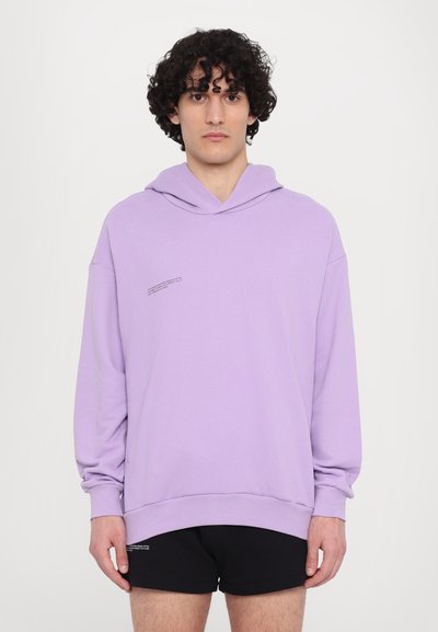 Sweatshirt com capuz em lavanda, com um bolso canguru frontal e punhos canelados. Apresenta um detalhe de texto minimalista no peito. Tecido de textura suave.
