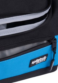 Zwarte en blauwe ritstas met een gestructureerde stof, voorzien van een logo patch en contrasterende binnenvoering. Meerdere zichtbare compartimenten.