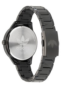 Montre-bracelet en acier inoxydable noir avec un boîtier rond, une lunette texturée et un bracelet maillé. L'arrière présente le logo de la marque et une finition polie.