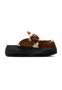 Chunky loafers med sort platformsål, overdel i brunt og hvidt kvægskind og metallisk logo detalje på remmen, set fra siden på hvid baggrund.
