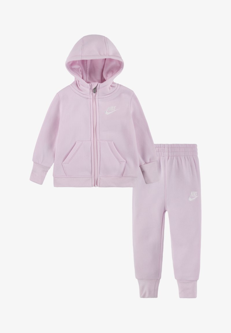 Conjunto de sudadero e calças cor-de-rosa feito de tecido macio, com um fecho na frente, dois bolsos e o logotipo da Nike em branco em ambas as peças.