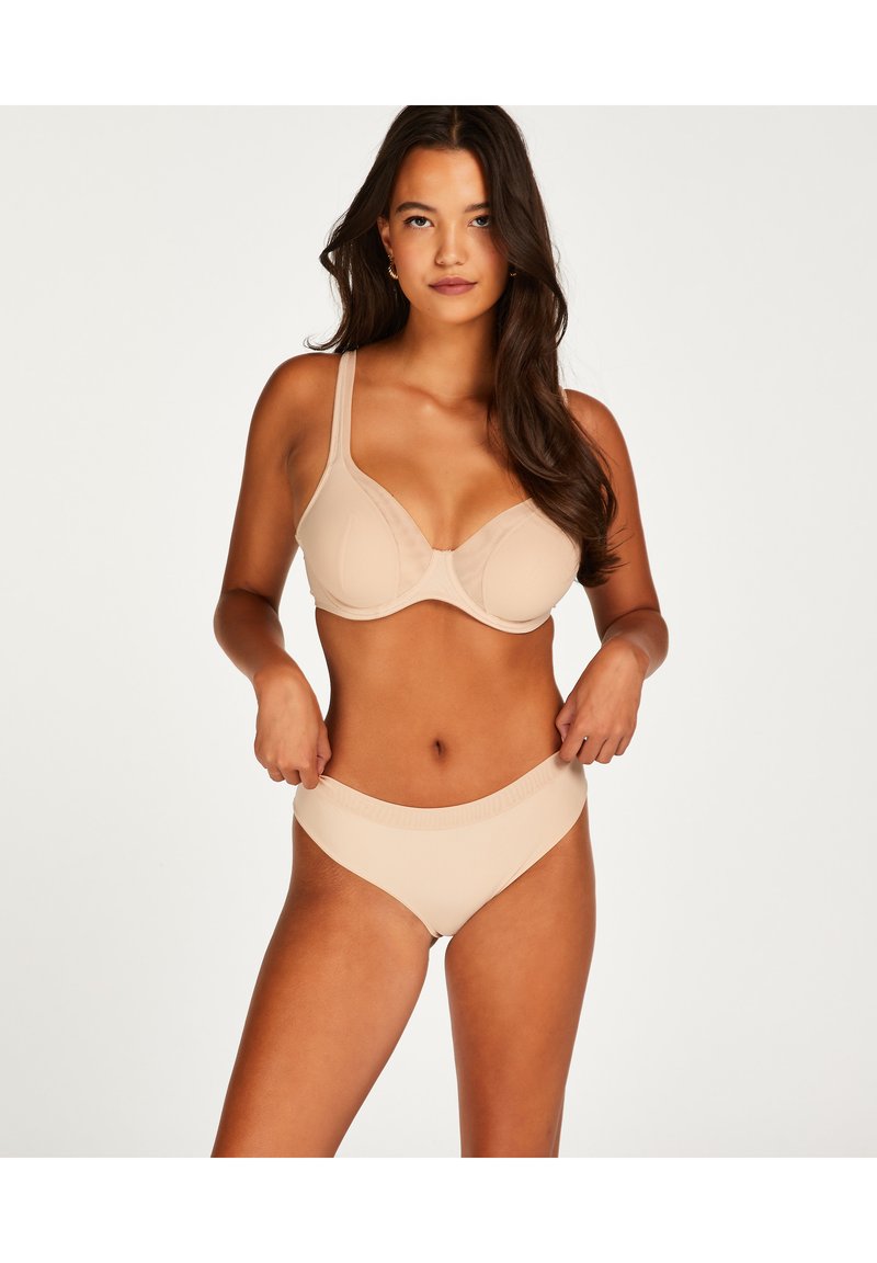 Nude naadloze bh en bijpassende slip met verstelbare bandjes. Zachte, rekbare stof met een gladde textuur en minimalistisch ontwerp.