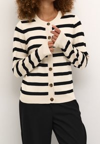 Schwarz-cream gestreifter Cardigan mit langen Ärmeln, Knopfverschluss und gerippten Bündchen. Mit großen braunen Knöpfen und einer weichen Textur.