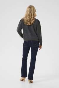 Maglione grigio a maglia con maniche lunghe, aderente in vita, abbinato a jeans scuri blu, svasati alle caviglie, indossato con tacchi alti beige.