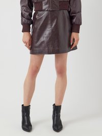 Bordeaux leren minirok met een gladde textuur en een getailleerd silhouet, gecombineerd met zwarte leren enkellaarzen met een spitse neus.