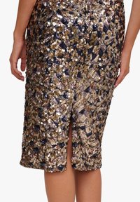 Gonna di paillettes con design a patchwork in oro, bronzo e blu navy. Include uno spacco posteriore e una finitura testurizzata per un aspetto dinamico.