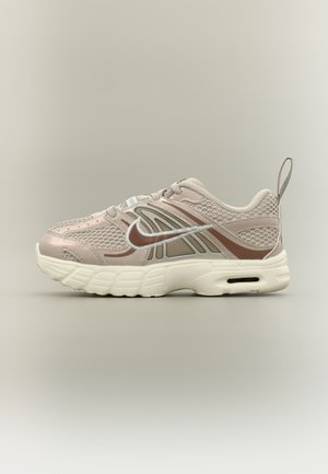 Baskets de sport beige clair et marron avec tige en mesh, semelle blanche, logo Nike swoosh et languette au talon.
