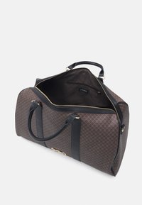 Sac de sport à motif marron avec quincaillerie dorée, accents en cuir noir, doubles poignées et un intérieur spacieux avec fermeture éclair.