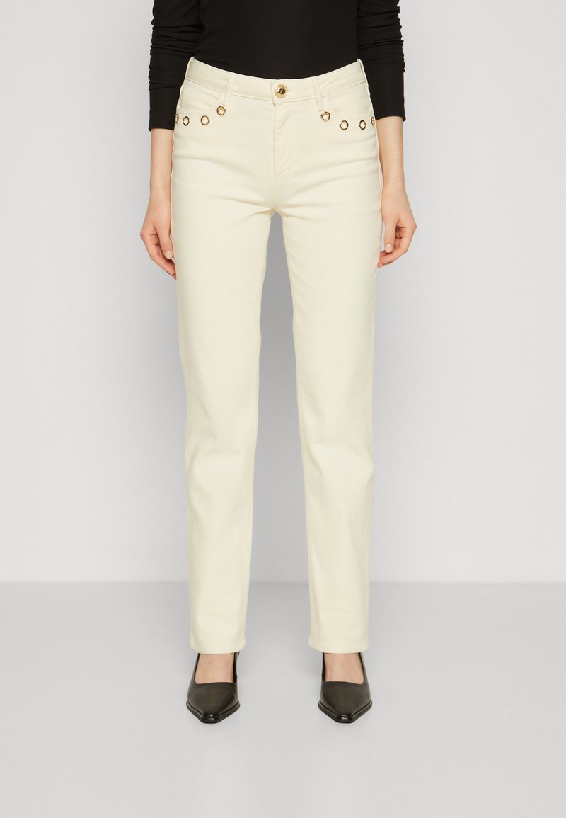 Jeans de pierna recta color crema con herrajes en tono dorado y ojetes decorativos a lo largo de los bolsillos delanteros. Fabricados en una tela suave.