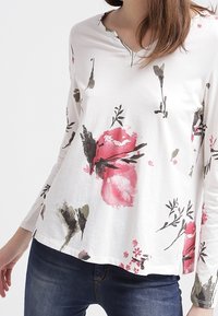 Vit långärmad skjorta med rosa och gröna blommor, V-ringning och avslappnad passform. Mjuk tyg med subtil textur.