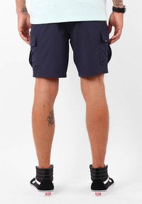 Shorts cargo navy avec poches latérales, fabriqués en tissu léger. Associés à des baskets montantes noires avec des accents blancs.