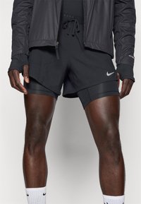 Schwarze Laufshorts mit elastischem Bund und Kordelzug. Merkmale des Nike-Logos in Silber, geschichtetes Design und atmungsaktives Material.