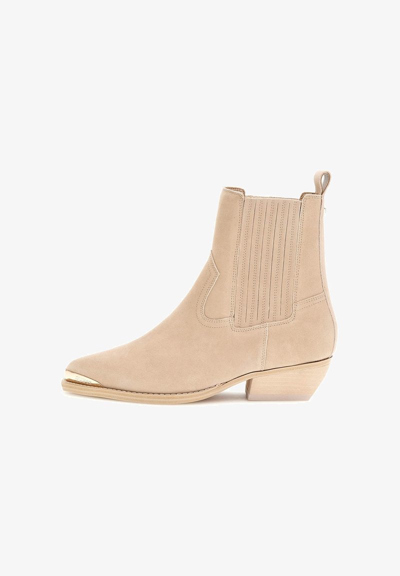 Botín de ante beige con punta afilada, diseño acanalado en los lados, un tacón pequeño y un detalle en tono dorado en la punta.