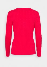 Pull en tricot côtelé rouge, à manches longues, de forme ajustée et col rond. Présente des motifs en relief en forme de câble sur le tissu.