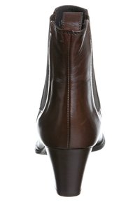 Bottines en cuir marron avec un talon effilé, des panneaux latéraux élastiques, une texture lisse et des détails de couture le long des coutures.