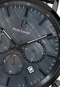 Reloj de pulsera negro con un dial texturizado de color gris oscuro, tres subdiales con patrones de círculos concéntricos, y marcadores y manecillas de hora plateados.