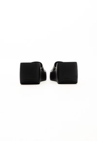 Sandale negre cu platformă, cu toc pătrat, fabricate dintr-un material neted, având un design slip-on și o talpă texturată pentru aderență.