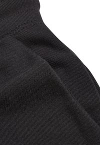 Tela negra con una textura acanalada que muestra las costuras. El material es suave y ligeramente elástico, sin patrones o acentos notables.
