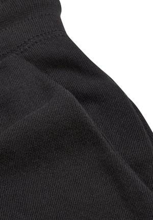 Tessuto nero con una trama a coste che mostra le cuciture. Il materiale è morbido e leggermente elastico, senza motivi o dettagli notevoli.