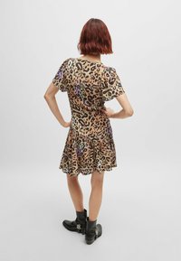 Leopard print dress with short sleeves, flared skirt, and a gathered waist. Worn with black ankle boots featuring metal accents.