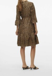 Leopardmönstrad klänning med åtsittande midja, trekvartslånga ärmar, vågig nederkant och lätt material. Buren med svarta öppna klackskor.