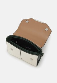 Piccola borsa a tracolla rettangolare con fronte crema, lati verdi e patta marrone chiaro, aperta per mostrare il compartimento centrale con zip e chiusura magnetica.