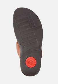 Bruine leren schoenzool met een gestructureerde zwarte rubberen onderkant. Voorzien van een geperst merkteken en een rode ronde inzet met golfpatroon.