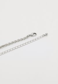 Silver metal chain with a lobster clasp, featuring oval links and a ball accent at the end. Smooth texture and polished finish.