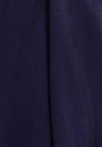 Mörkblå tyg närbild som visar en slät textur med en subtil lyster, med två överlappande sektioner för en lagerliknande effekt.