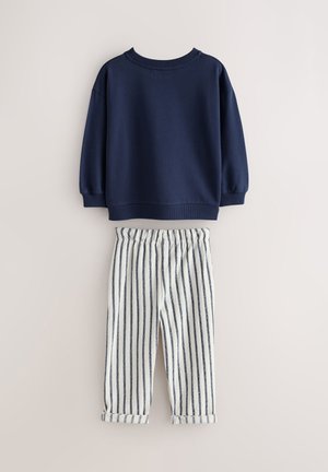 Sudadera azul marino con cuello acanalado y mangas largas con puños, combinada con pantalones a rayas crema y azul marino con cintura elástica.