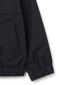 Schwarze, leichte Jacke mit geripptem Bündchen, Seitentasche und glatter Stofftextur in entspannter Silhouette.