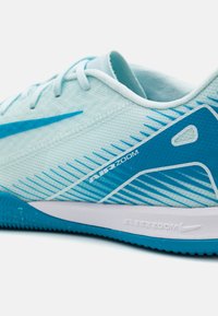 Baskets de sport bleu clair avec tige en mesh, accents bleu foncé, motif rayé, logo sur le côté et semelle blanche avec adhérence texturée.