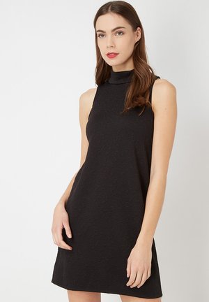 Vestido negro sin mangas con un cuello alto y un patrón floral texturizado, con un corte holgado que llega por encima de las rodillas.