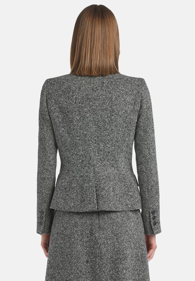 Blazer gris texturé avec une silhouette ajustée, fermeture à un bouton et détails de couture subtils, associé à une jupe assortie.