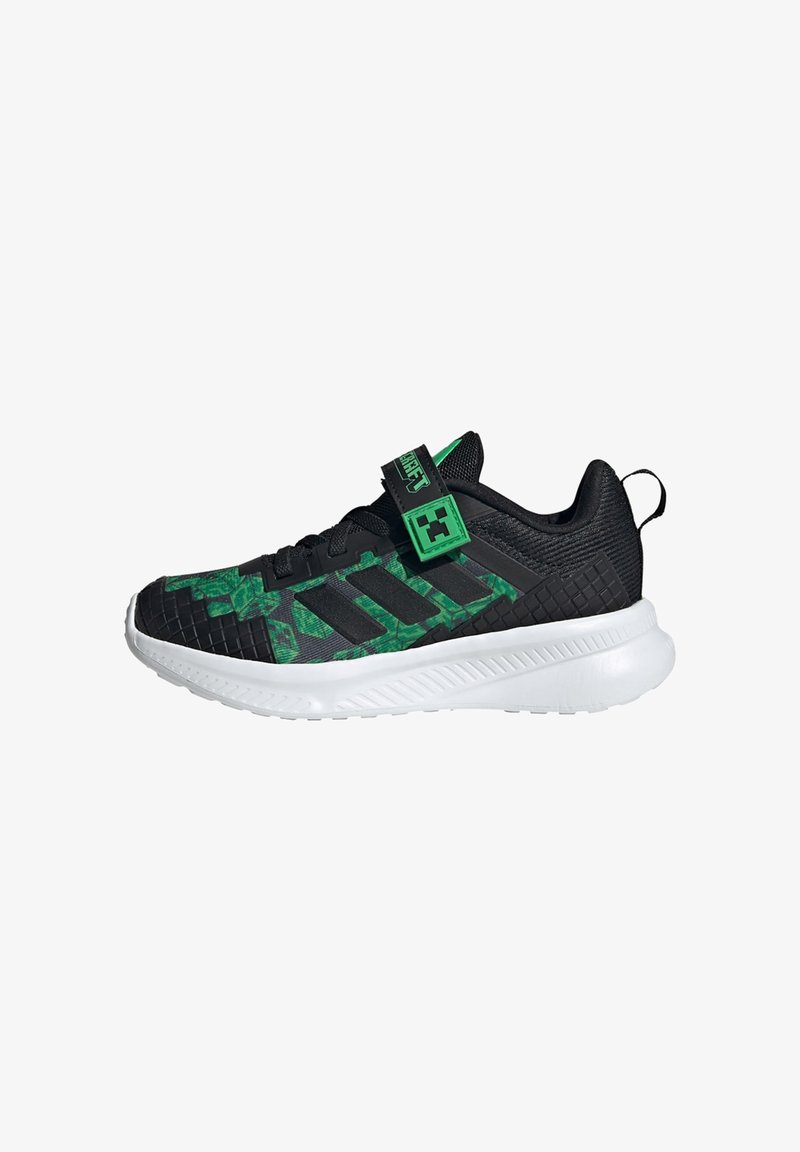 Zapatillas deportivas negras con detalles verdes, con parte superior texturizada, patrón geométrico, correa ajustable y suela blanca.