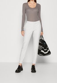 Grå långärmad bodysuit i kombination med vita skräddarsydda byxor, svarta blockklackade loafers och en svart-vit mönstrad tygväska.