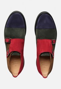 Mehrfarbige Wildlederschuhe mit roten, grünen, marineblauen und braunen Einsätzen. Zwei silberne Schnallen im roten Bereich veredeln das Design.