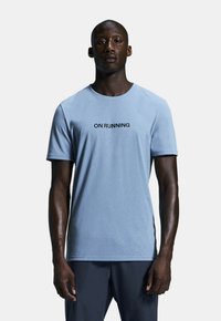 Light blue short-sleeve t-shirt made of soft fabric, featuring a black print that says "ON RUNNING" across the chest.