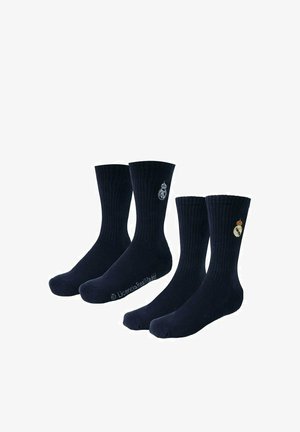 Dwie pary czarnych, prążkowanych skarpetek do kostek z białymi i kolorowymi logo Realu Madryt po bokach.