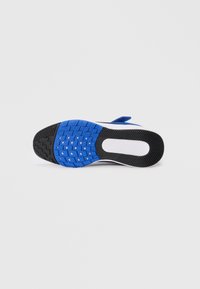 Semelle de chaussure en caoutchouc bleu avec une texture antidérapante, comportant une section noire et des accents blancs, conçue avec des sculptures pour une meilleure adhérence.