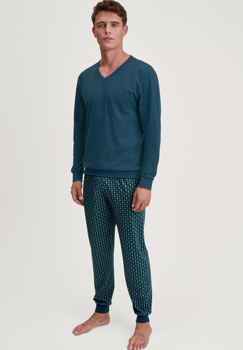Completo pigiama da uomo: maglia teal a maniche lunghe con scollo a V e tasca, pantaloni a fantasia verde scuro con dettagli floreali bianchi, polsini elasticizzati.